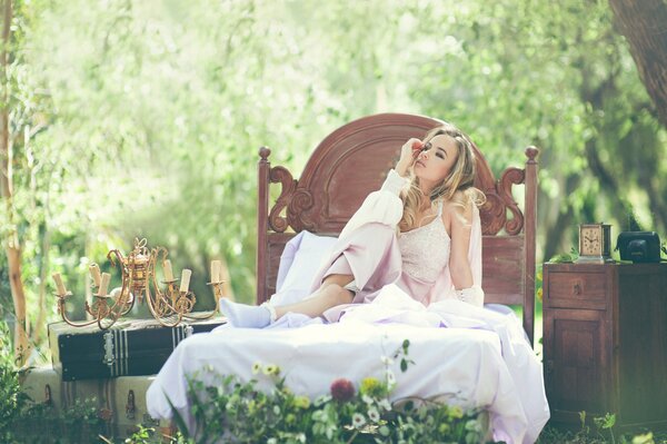 A girl is sitting on a cot in the middle of the forest