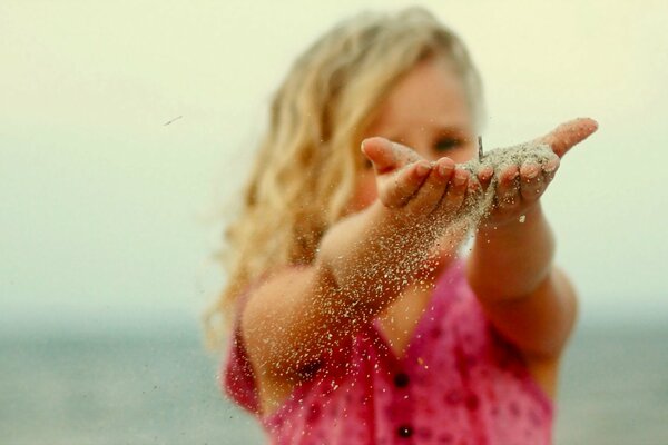 Fille et le sable qui coule à travers les doigts