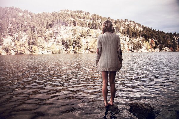 Chica descalza en el fondo de un lago con un hermoso paisaje