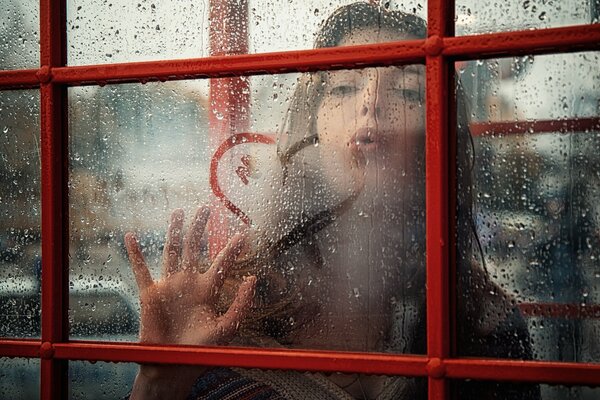 Dziewczyna rysuje serce na zaparowanym oknie