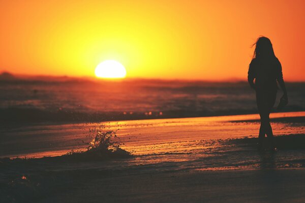 A girl on the seashore in the sunset spray