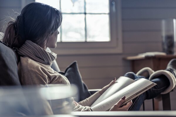 Девушка сидит в кресле и читает журнал