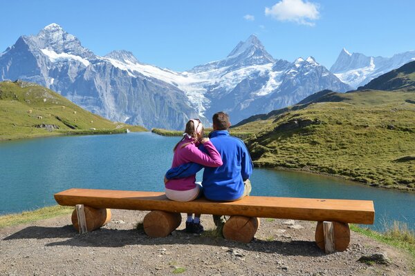 La pareja se sienta en un banco y Mira hacia las montañas