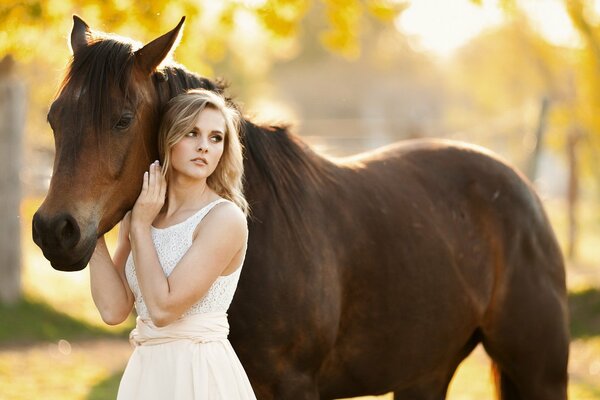 A girl in a white dress strokes a horse