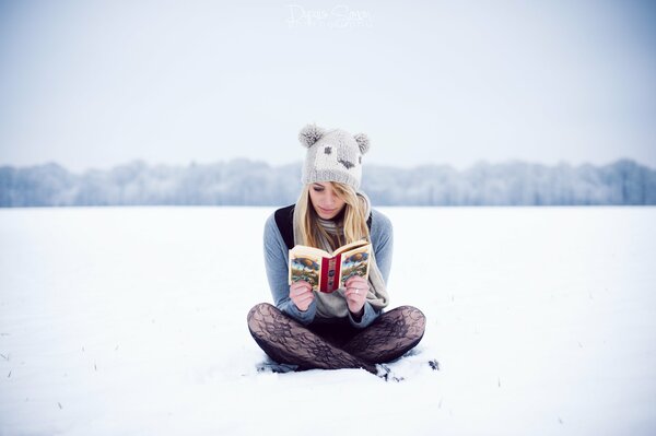 La ragazza con il cappello legge un libro sulla neve