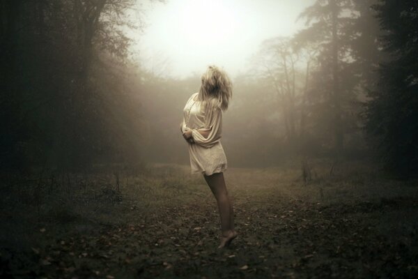 A girl standing in a misty forest