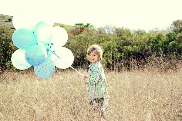 A little boy in a field with balloons