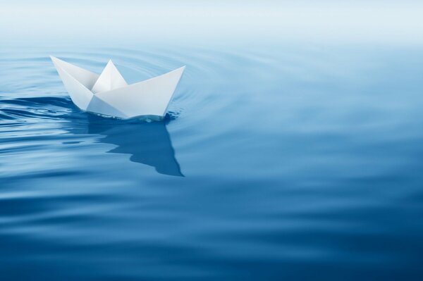 Отважный бумажный кораблик плывущий по синим волнам