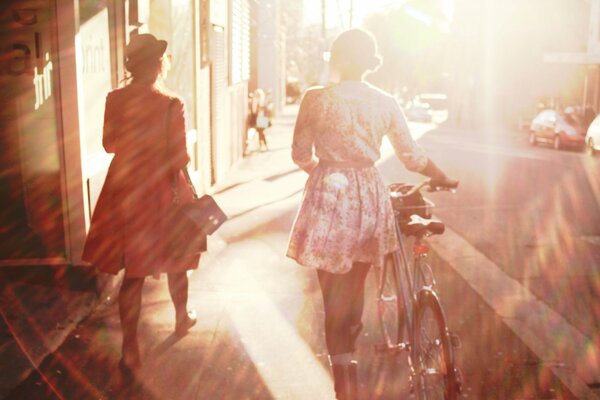 A girl with a bicycle on a sunny street