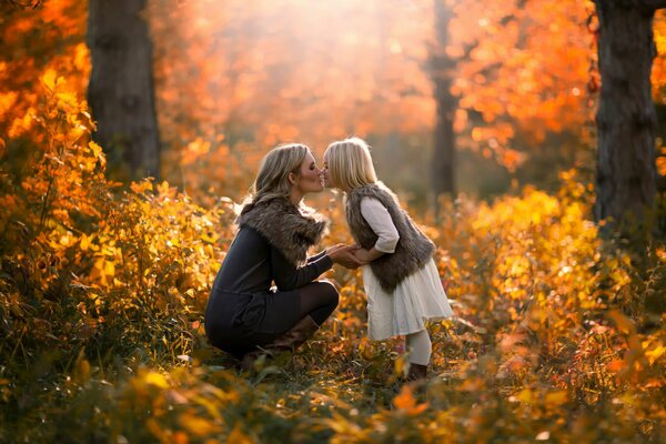El beso de la hija y la madre en el fondo de los árboles amarillos