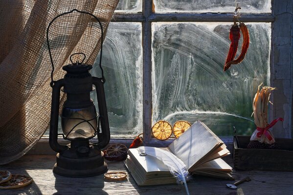 A book with a pen and a kerosene lamp on the windowsill