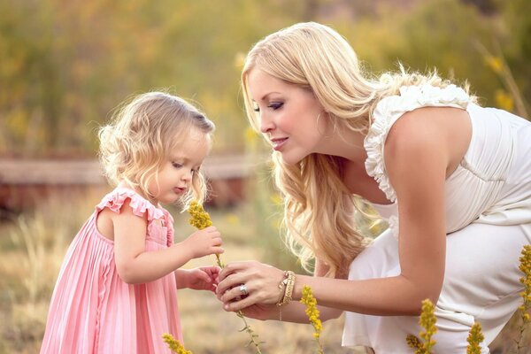 A woman hands a flower to a girl