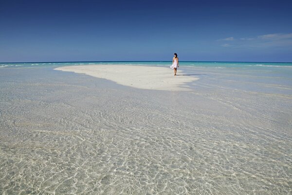 A girl walks on white sand