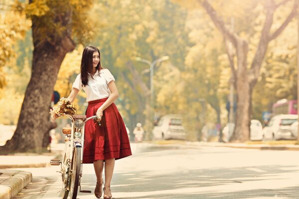 A girl in a red skirt on a bicycle