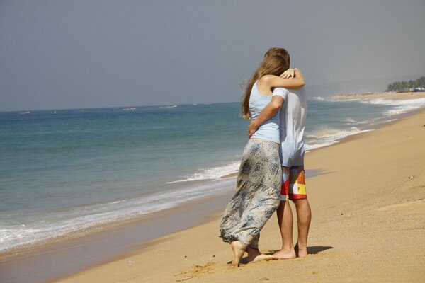 Парень и девушка обнимаются на берегу океана