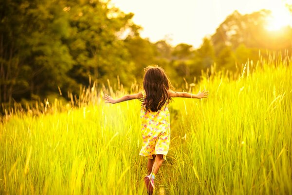 A girl runs across a field in the sunlight