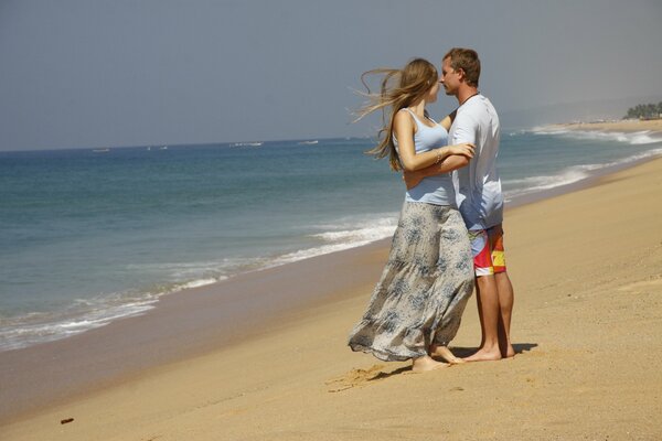 Pareja enamorada de pie en la orilla del mar