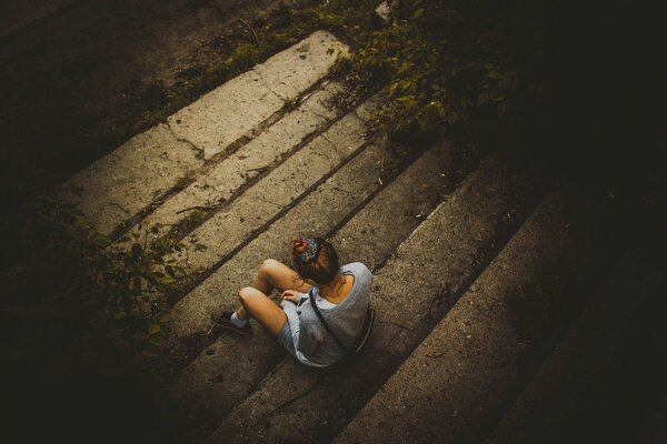 Одинокая девушка сидит на ступеньках