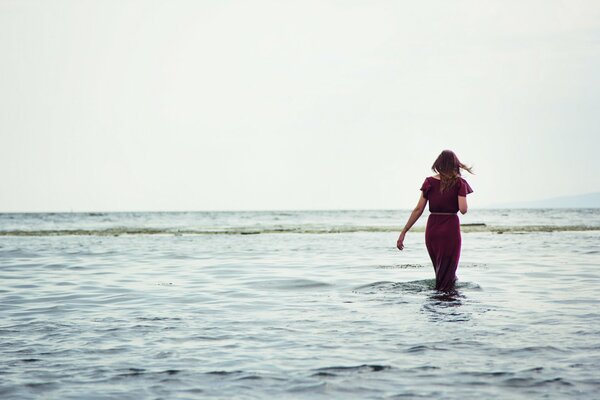 The brunette walks in the water to the horizon