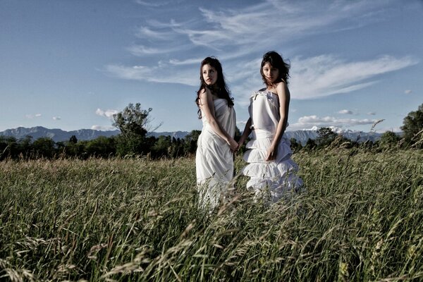 Chicas con vestidos blancos en el campo verde