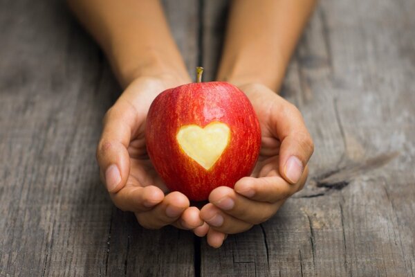 Apfel mit geschnittenem Herz in den Händen