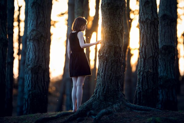 Mädchen im schwarzen Kleid in der Nähe von einem Baum