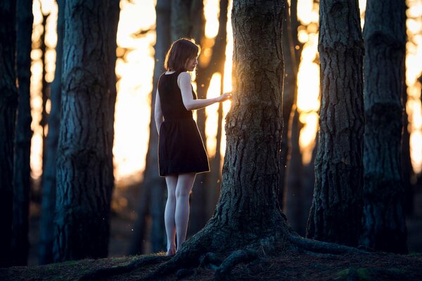Dziewczyna w czarnej sukience w pobliżu drzewa