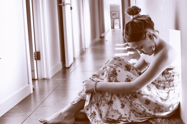 Foto Monocromática de una niña triste sentada en un pasillo vacío