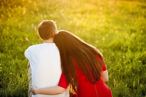 A guy and a girl hugging while sitting on the grass