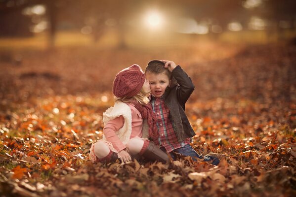 Девочка и мальчик целуются на фоне осеннего пейзажа