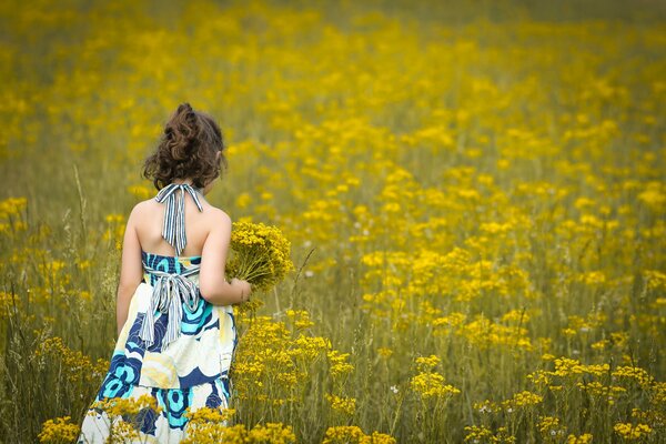 Una niña en un vestido ligero con un ramo de flores entre las flores