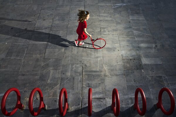 La petite fille dans une robe rouge court le cercle