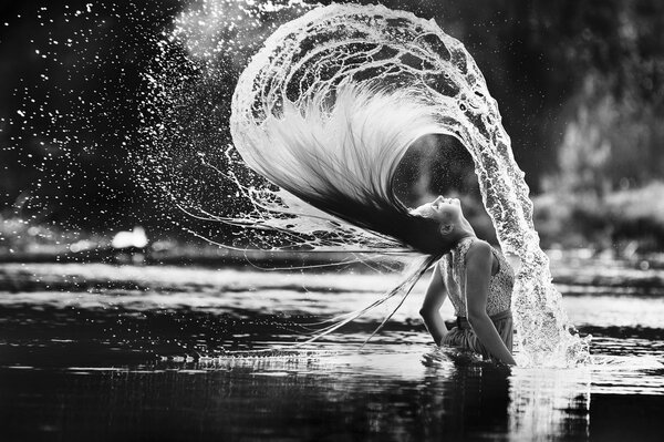 The girl made splashes on the water waving her wet hair