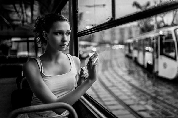 Eine Ballerina fährt in einer Straßenbahn und schaut aus dem Fenster auf eine entgegenkommende Straßenbahn