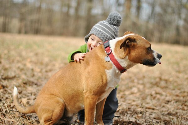 The boy hugs the dog with a smile