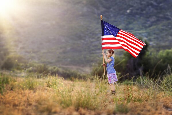 Bambina nel campo con la bandiera americana