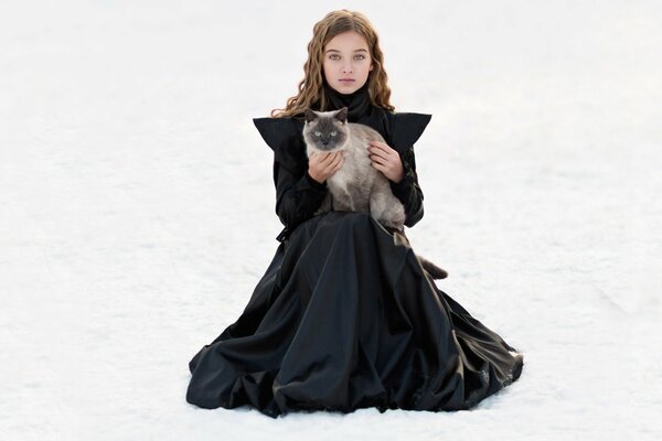 Photo of a girl in the snow with a white cat