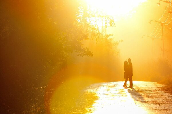 Пара стоит на дороге в лучах закатного солца