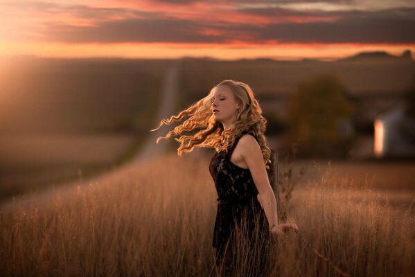 Девушка в траве с ветром в волосах