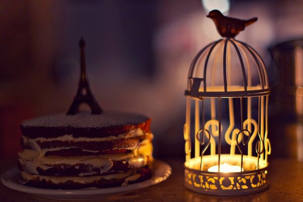 Large-format wallpaper with a sponge cake decorated with the Eiffel Tower and a cage with a candle and a bird for your mood