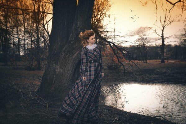 A girl in a dress stands in an autumn park