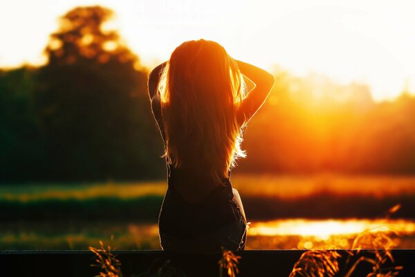 La silhouette de la jeune fille sur le coucher du soleil du soir