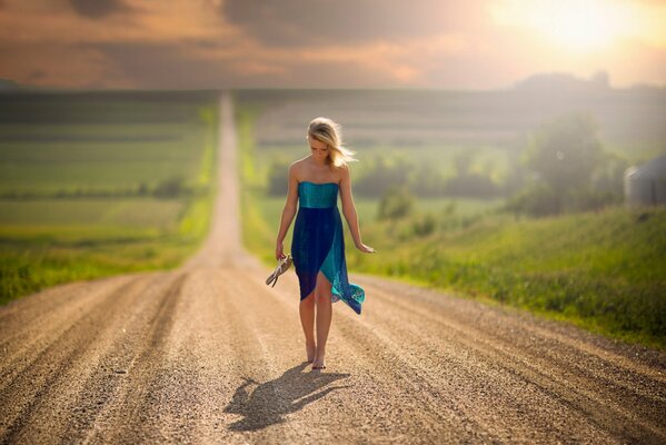 Ragazza che cammina da sola sulla strada della polvere a piedi nudi