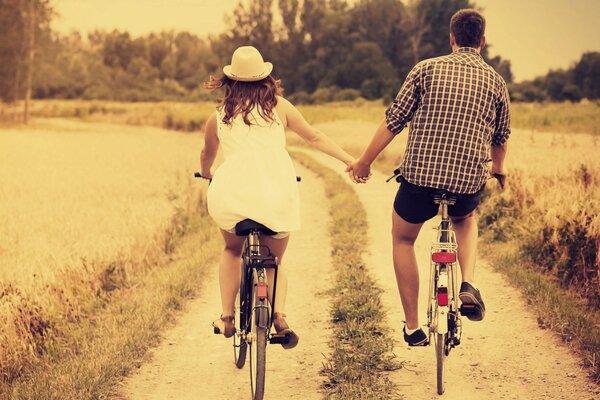 Chico y chica montando en bicicleta tomados de la mano