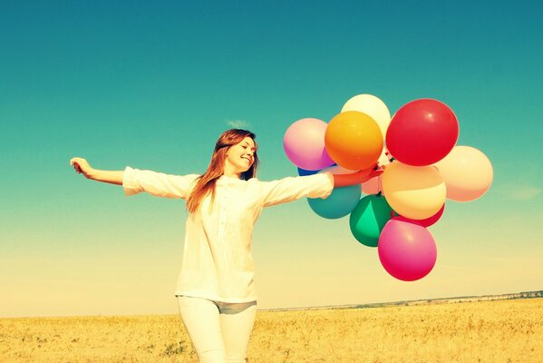 Szczęśliwa dziewczyna z balonami na tle natury