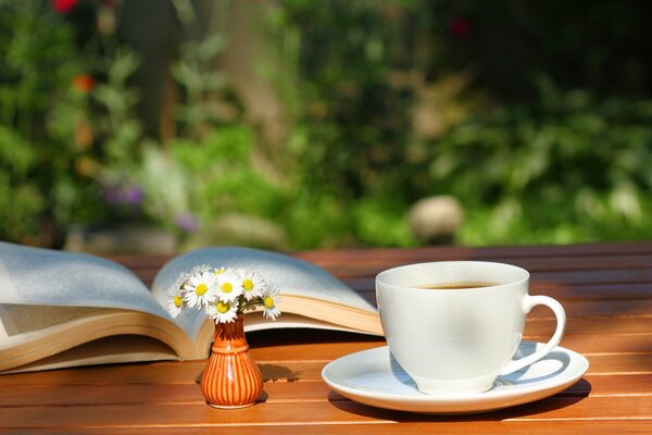 Stillleben aus einer Tasse Tee, ein Blumenstrauß aus Gänseblümchen im kleinen und ein Buch