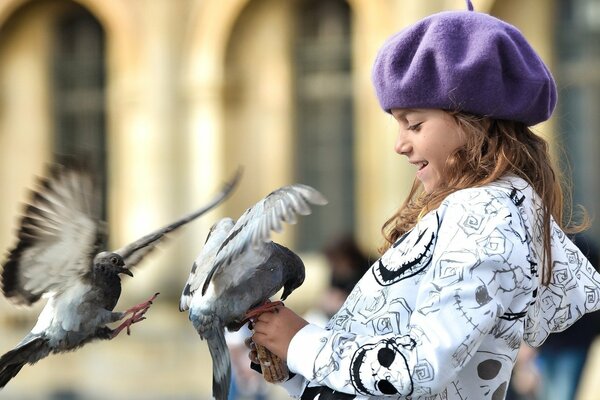 Девочка в шапке кормит голубей