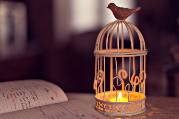 A notebook on the table with a decorative cage inside a candle