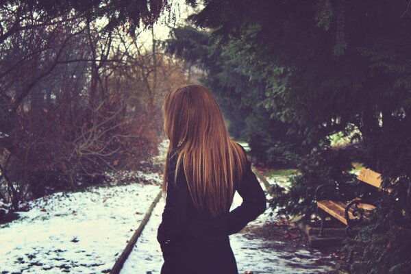 Ragazza con i capelli lunghi in panchina in inverno