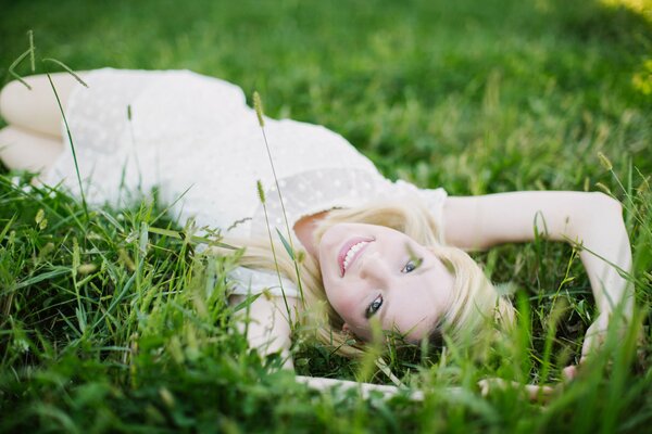 Jeune fille blonde souriante sur l herbe